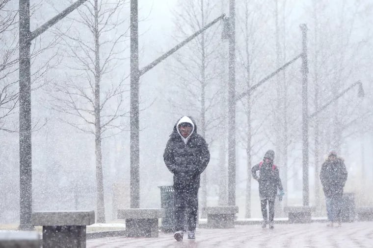 Pedestrians are caught in a snow squall on the campus of the University of Pennsylvania in Philadelphia on Wednesday. Thursday will be even colder.