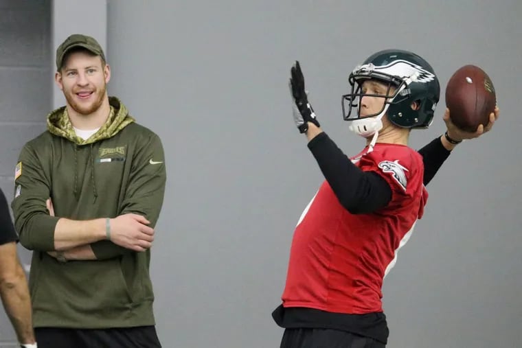 Injured quarterback Carson Wentz, left, watches current starter Nick Foles warm up during Eagles practice at the NovaCare Complex in South Philadelphia on Saturday, Jan. 27, 2018.