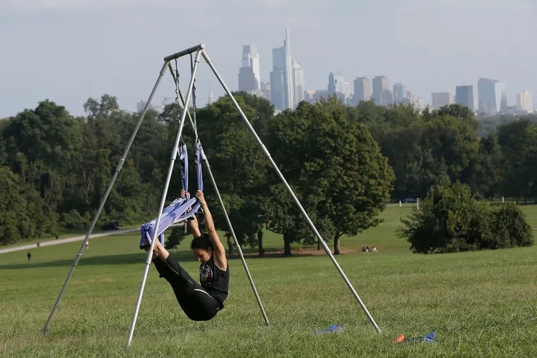 Yoga instructor Sylvia Granato of Hammonton, N.J., warms up as she waits for a student at Belmont Plateau in Philadelphia's West Fairmount Park on Friday, Sept. 18, 2020. Granato, who teaches at Your Space Yoga Studio in Hammonton, also travels around the region with her portable trapeze stand to give yoga trapeze lessons. She said the coronavirus pandemic has increased demand for outdoor sessions.
