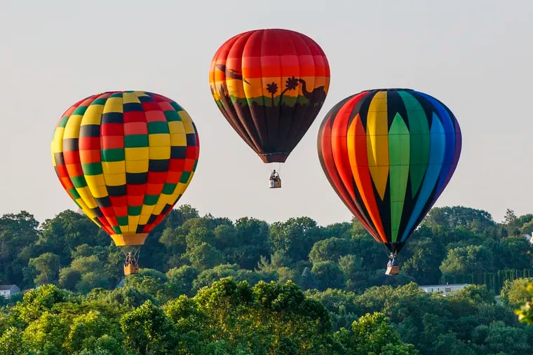 Three hot air balloons float over Chester County after taking off from New Garden Flying Field in Toughkenamon at sunrise Sunday, June 23, as part of the 13th Annual Chester County Balloon Festival.