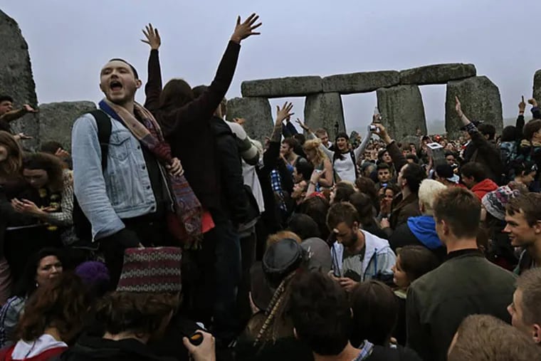 People raise their hands in celebration during the summer solstice shortly after 4:52 am at the prehistoric Stonehenge monument, near Salisbury, England, Friday, June 21, 2013. Following an annual all-night party, thousands of New Agers and neo-pagans danced and whooped in delight at the ancient stone circle Stonehenge, marking the summer solstice, the longest day of the year. (AP Photo/Lefteris Pitarakis)