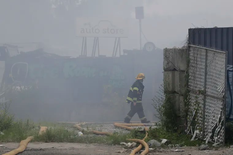 A firefighter walks in the smoke during a junkyard fire at 61st Street and Passyunk Avenue in Southwest Philadelphia on Monday.