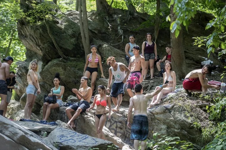 People congregate at the top of the rocks and cliffs at Devil’s Pool in the middle of the Wissahickon Creek June 28, 2017. Some people jumped off into the refreshing waters below. Area residents say the foot traffic has gotten out of control and some are calling for the 15-foot watering hole to be filled in with rocks. Complaints include: out of town cars parked on lawns, trash and people urinating on their property. CLEM MURRAY / Staff Photographer