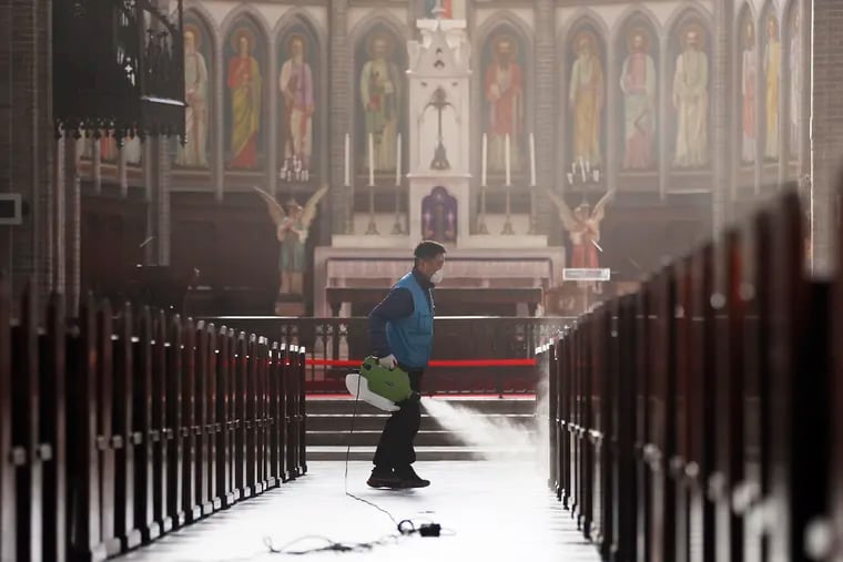 A worker wearing a face mask sprays disinfectant as a precaution against the new coronavirus at Myeongdong Cathedral in Seoul, South Korea, Wednesday, Feb. 26, 2020.