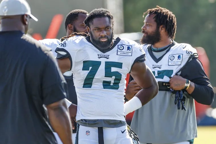 Philadelphia Eagle defensive end, Josh Sweat, #75, center, listens to his assistant coach, left, while Micahel Bennett, #77, right, talks to Fletcher Cox before pracitce begins at the Eagles training camp at the NovaCare Center on August 2, 2018. MICHAEL BRYANT / Staff Photographer