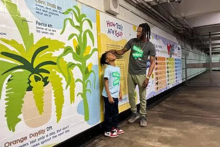 Keith "KJ" Stafford Jr., 7, and his father Keith Stafford Sr., Philadelphia rapper K-Staff, check out one of the installations at the Tasker-Morris station of SEPTA's Broad Street Line.
