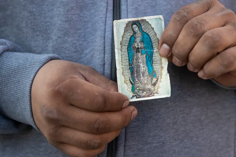 David Meneses, propietario de la Cafetería y Panadería Las Rosas en el sur de Filadelfia, sostiene una foto de Nuestra Señora de Guadalupe, mientras posa para un retrato, el jueves 10 de diciembre de 2020.