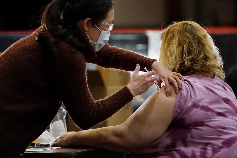A health-care worker administers a COVID-19 vaccine at South Philadelphia High School in South Philadelphia on Thursday, March 4, 2021. The school is one of six sites across the city where teachers and school personnel can receive vaccines.
