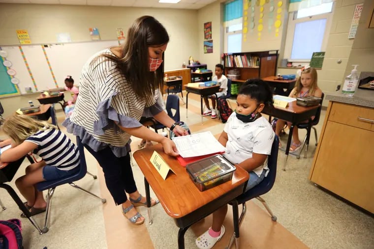 Corinth Elementary School third-grade teacher Brooke Marlar helps her new student Navaeh Malone get started with her assignment on the first day back to school on July 27.