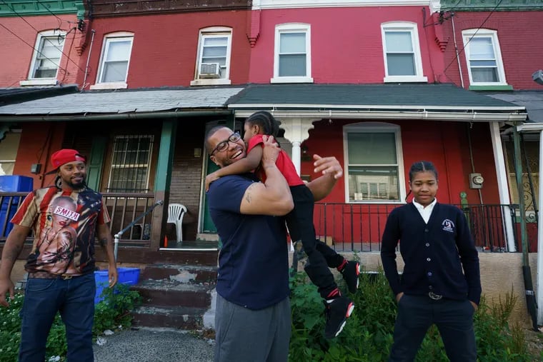 Anthony Thornton, looks on as his brother Terrance Lewis, center, hugs his nephew Sharif Thornton, in West Philadelphia, the day Terrance was released from prison, May 22, 2019.