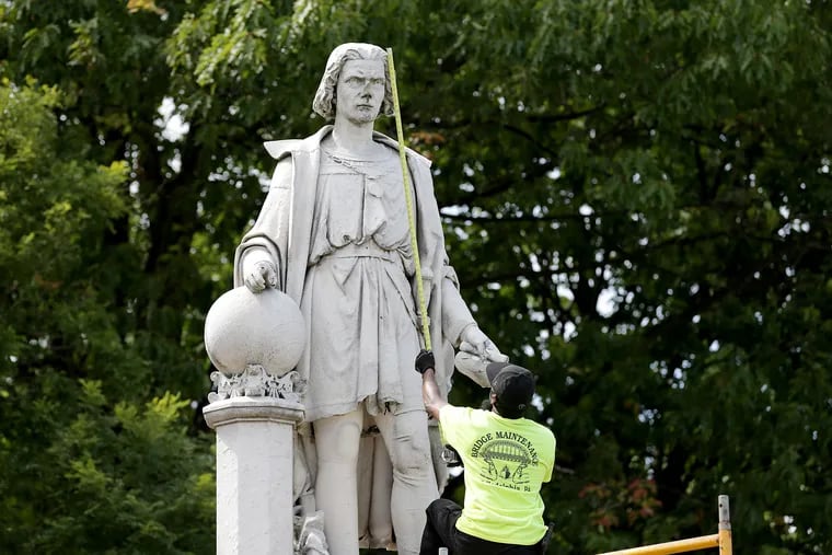 A worker takes a measurement as they prepare to box the Christopher Columbus statue in Marconi Plaza in Philadelphia, Pa. on June 16, 2020.