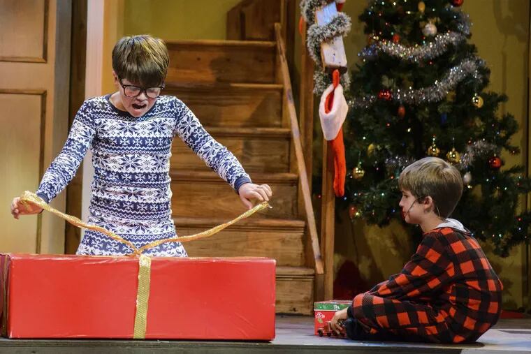 (From left to right:) Ralphie (Ben Pedersen) opens his Christmas gift while little brother Randy (Aidan Crane) watches with anticipation. From "A Christmas Story" at The Media Theatre.