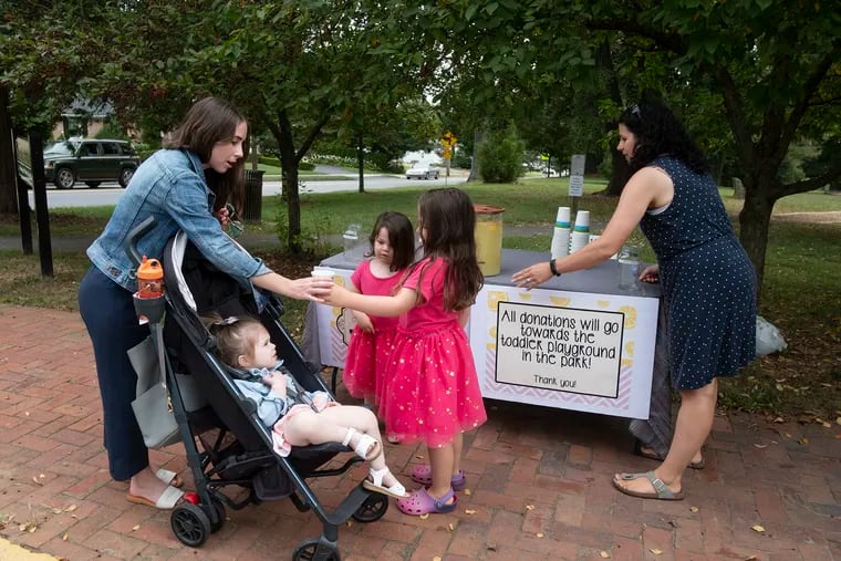 Adelaide (left) and Briar Fieldhouse make their sales pitch to Julie Novotny and her daughter Tallulah, as mom Chantale secures a sign on the lemonade stand in Marshall Square Park.