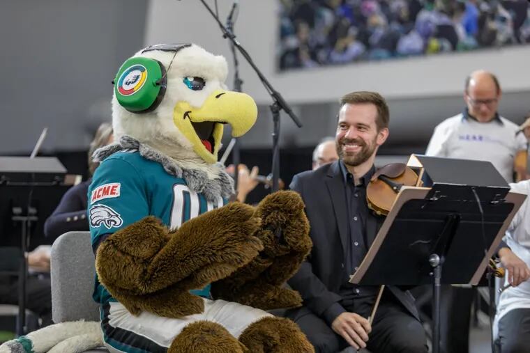 Philadelphia Eagles mascot Swoop shares a moment with Philadelphia Orchestra assistant concertmaster Marc Rovetti at the NovaCare Complex before the orchestra's performance Sunday afternoon.