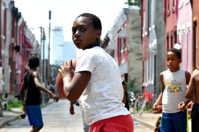 Nyzir, 10, prepares to throw the ball as neighborhood children play on the closed 2400 block of N. Bouvier Street, in North Philadelphia, PA, on August 7, 2018.