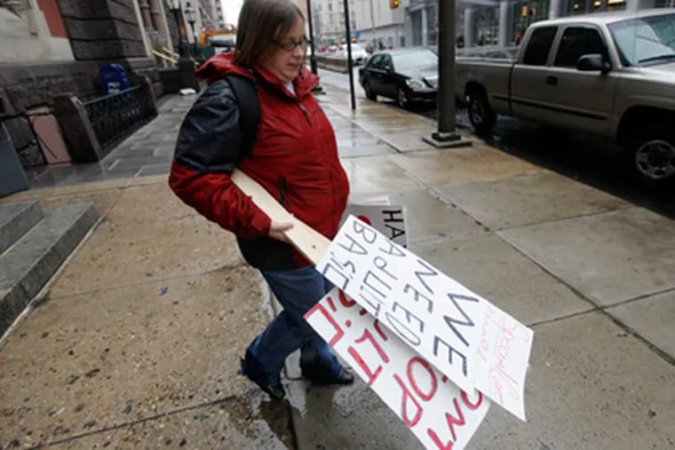 Antoinette Kraus of the Philadelphia Unemployment Project carries signs to a van in Philadelphia on Monday, preparing for a candlelight vigil in Harrisburg to protest the end of the program. (Matt Rourke / Associated Press)