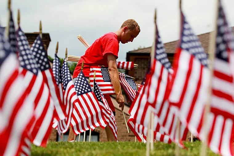 File: Michael Ciavarelli places one of 1,500 American flags that he and his father planted in the front lawn of Ciavarelli Funeral Home in Ambler Thursday, July 3, 2014.  MICHAEL BRYANT / Staff Photographer