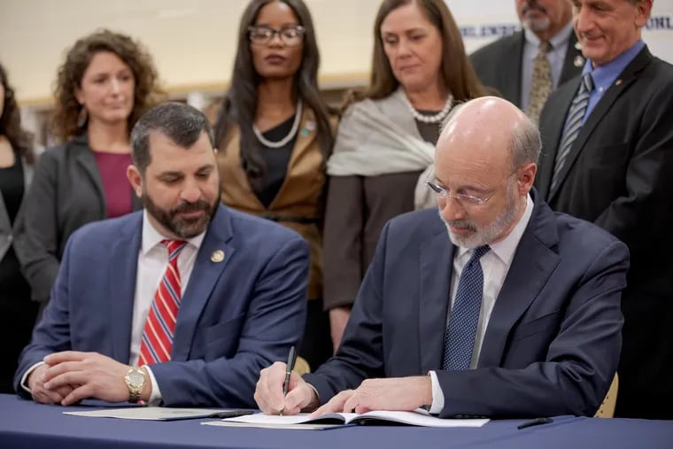 Gov. Tom Wolf (right) and State Rep. Mark Rozzi sign a package of three bills on the statute of limitations for victims of child sexual abuse in 2019.