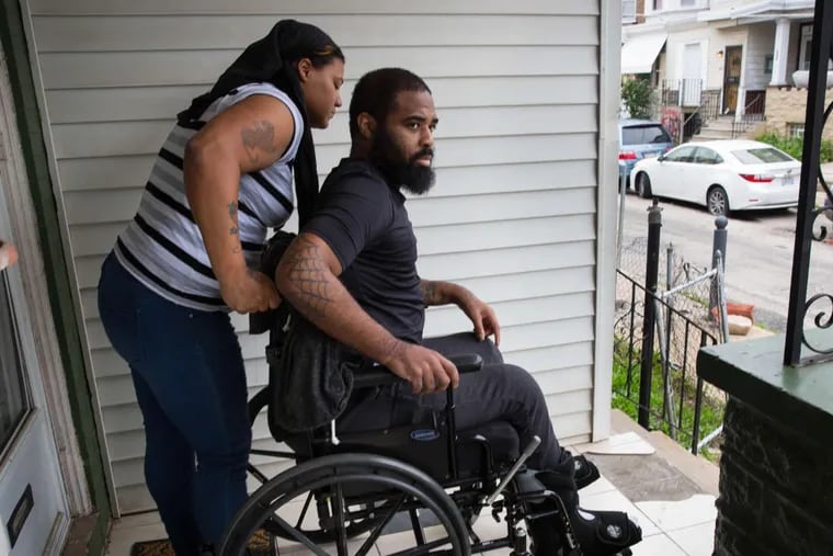 Tamira Brown, left, assists Jalil Frazier, right, with getting out of the living room and onto the front porch, though the multiple and steep stairs leading from the front porch to the sidewalk are a major issue.