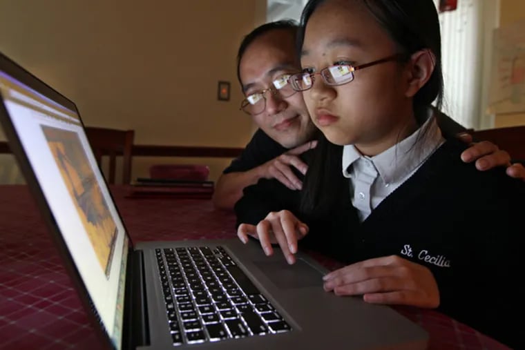 Josephine Nyugen, a sixth-grader at St. Cecelia, right, with her father, Joseph, left, plays the math game 'Into the Vortex' on the First in Math website. Josephine has won the FIRST in MATH national competition for the third time in a row. ( MICHAEL
BRYANT / Staff Photographer )