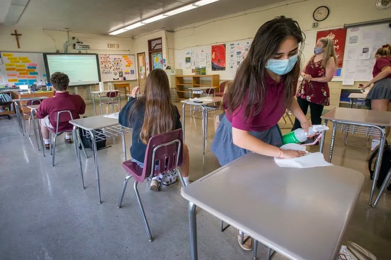 Nathania Mazahreh, 16, wipes down the desk in her English class at Holy Cross Prep Academy, Delran, N.J. Gov. Phil Murphy announced Friday that all K-12 students will have to wear masks in New Jersey