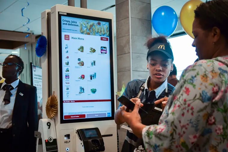 McDonalds employee Tiyanah Boyd assists customer Judy Dixon (right) with the new technology in the McDonald's at 7500 City Ave.