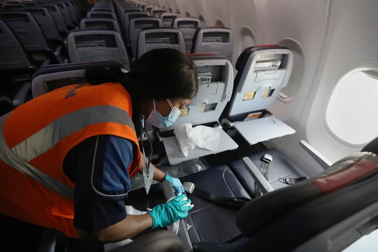 Joyce Bargor, a cabin cleaner for Prospect Airport Services, disinfects seats on an American Airlines plane between flights at Philadelphia International Airport on Tuesday, June 30, 2020. American Airlines plans to increase the number of flights from Philadelphia starting July 7.
