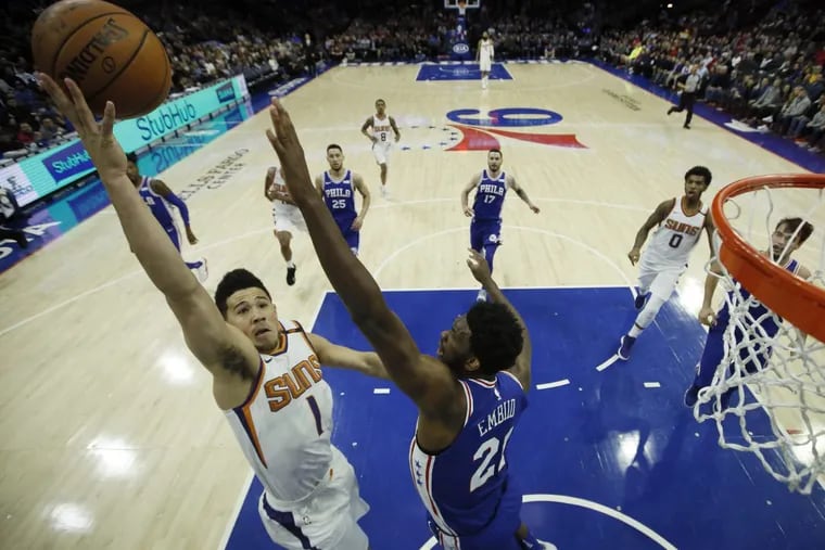 The Suns' Devin Booker goes up for a shot against 76ers center Joel Embiid during the first half Monday night.