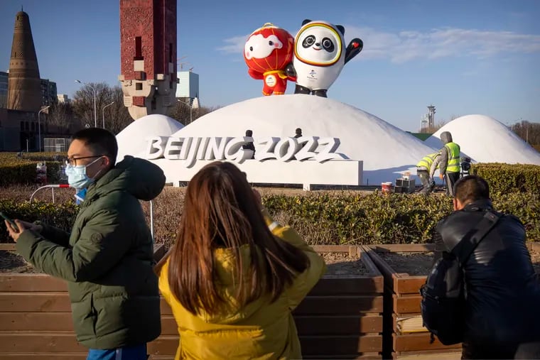 People wearing face masks to help protect against the coronavirus look at a display of the Winter Paralympic mascot Shuey Rhon Rhon (left) and Winter Olympic mascot Bing Dwen Dwen near the Olympic Green in Beijing.