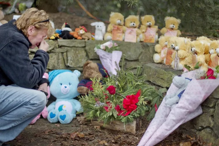 Cheryl Girardi, of Middletown, Conn., kneels beside 26 teddy bears, each representing a victim of the Sandy Hook Elementary School shooting, at a sidewalk memorial, Sunday, Dec. 16, 2012, in Newtown, Conn. A gunman walked into Sandy Hook Elementary School in Newtown Friday and opened fire, killing 26 people, including 20 children.(AP Photo/David Goldman)