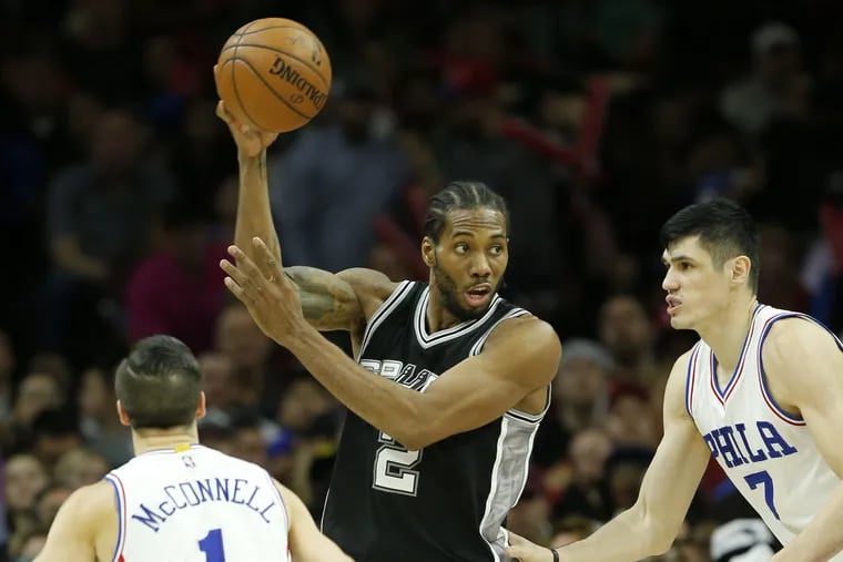 Kawhi Leonard moves the ball over the Sixers' T.J. McConnell and Ersan Ilyasova during a 2017 game.