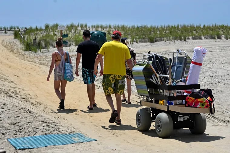 Beachgoers carry their stuff toward the sand dunes and the beach in Margate, outfitted for a day at the Jersey Shore, where ocean temperatures became a source of controversy.