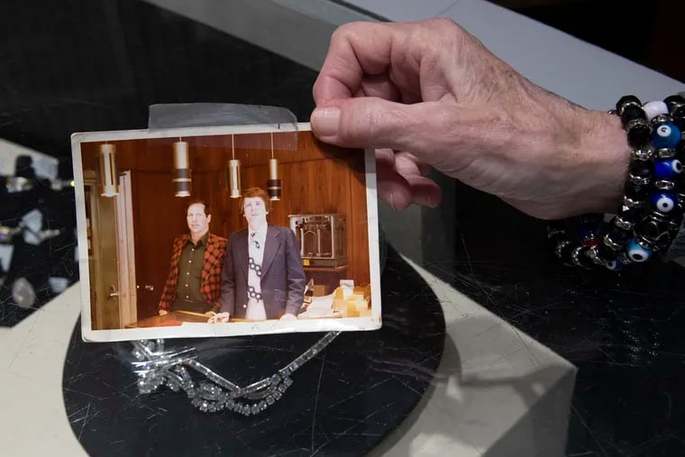 Becky Guise holds a photo of her late former boss and friend Michael Lauria (r) at Lauria's Jewelers in Philadelphia.