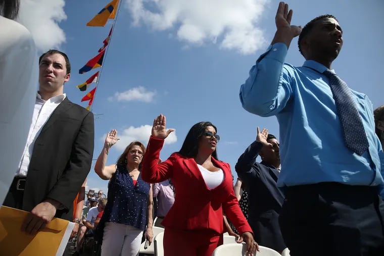 Sheyla Hershey, center, of Medford, N.J., originally from Brazil, recites the oath of allegiance during a naturalization ceremony on the Battleship New Jersey in Camden, N.J., on Thursday, July 4, 2019. Forty people from 23 countries were sworn in as U.S. citizens during the ceremony, one of more than a hundred held on the 4th of July holiday.