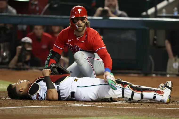Phillies slugger Bryce Harper checks on Arizona Diamondbacks catcher Gabriel Moreno after a collision at home plate on a double steal in Game 5. Moreno remained in the game.