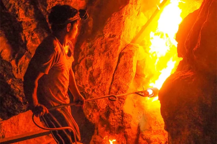A gold miner uses heat to soften rock in a tunnel on the Indonesian island of Sulawesi. Tunnel collapses are common.