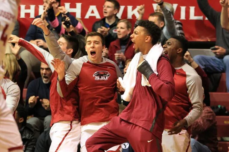 The St. Joseph’s bench including injured star Charlie Brown celebrate after a Taylor Funk 3-point shot in the 2nd half against Duquesne at Hagan Arena on Feb. 17, 2018.