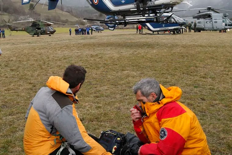 Rescue workers watch as a helicopter takes off in Seyne-les-Alpes, France. Investigators found a rocky mountainside strewn with plane parts.