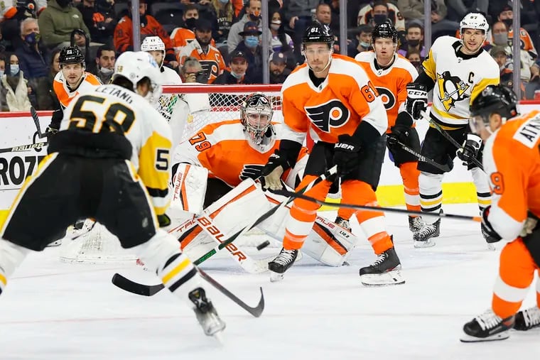 Flyers goaltender Carter Hart and defenseman Justin Braun watch a shot by Pittsburgh Penguins defenseman Kris Letang.