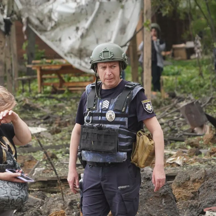 A woman cries as police officers inspect the site of the Russian missile attack that hit a recreation area killing five people and injuring 16 in the outskirts of Kharkiv, Ukraine on May 19.