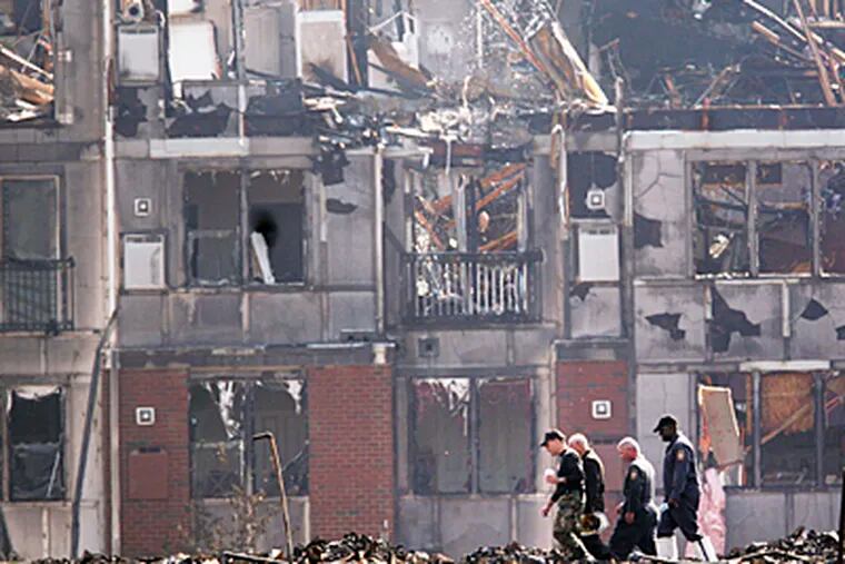 Fire investigators sift through the rubble of an apartment complex in Conshohocken Thursday morning after a ten alarm blaze last night that left 375 people homeless.  (Laurence Kesterson / Inquirer)