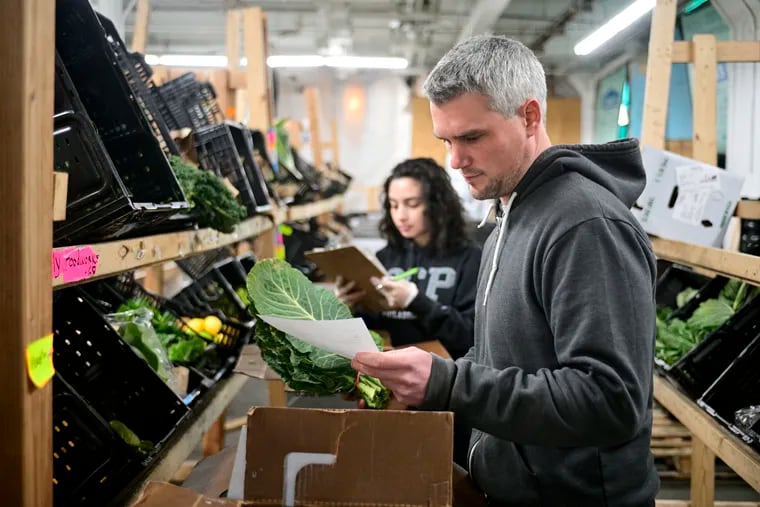 Dylan Baird, co-founder of Philly Foodworks, helps as a crew fills orders of winter produce. Philly Foodworks collaborates with local farms (and two nonlocal produce sources) plus local makers (coffee roasters, bakers, etc.) to fill grocery orders via an online marketplace.