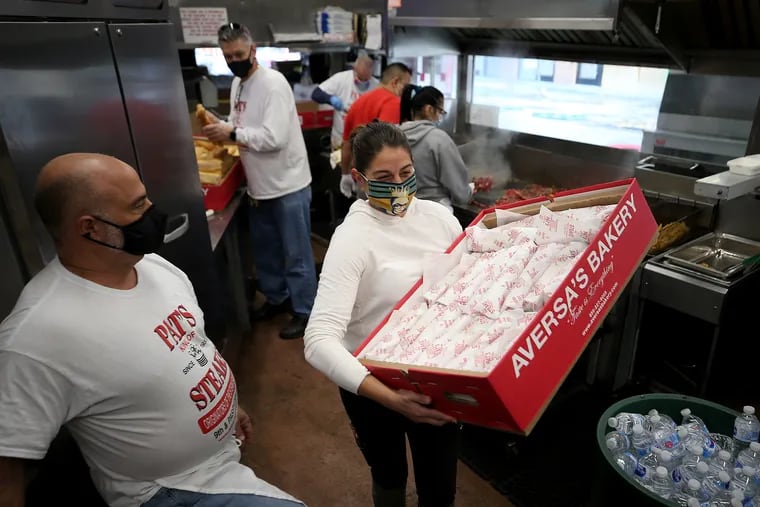 Abbe Stern (right), project manager for Step Up to the Plate, picks up one of several boxes of cheesesteaks at Pat’s King of Steaks, where owner Frank Olivieri sees her out the door.
