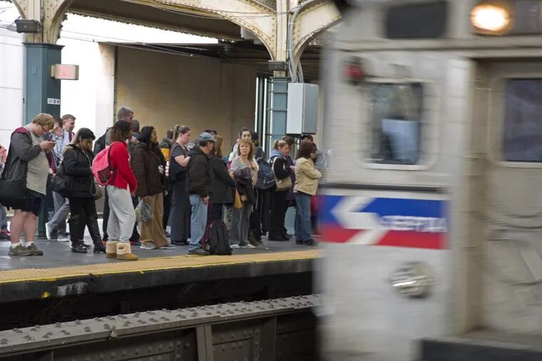 A Regional Rail train arrives as commuters wait on the platform at 30th Street Station.