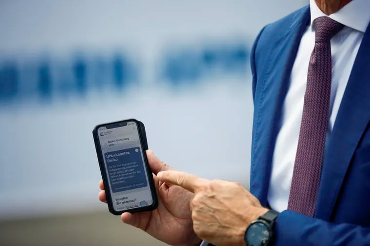 Timotheus Hoettges, CEO of Germany's telecommunications giant Deutsche Telekom AG, holds a mobile phone as he attends the presentation of a new contact-tracing smartphone app in June.