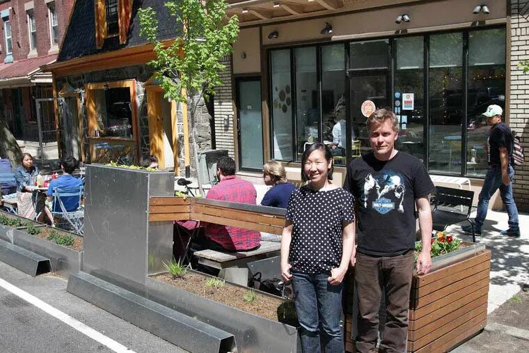 Jeanne Chang, left,  owner of Lil' Pop Shop, and Tom McCusker, right, owner of Honest Tom's, pose in front of the parklet outside their shops in West Philadelphia on May 6, 2014. ( DAVID MAIALETTI / Staff Photographer )