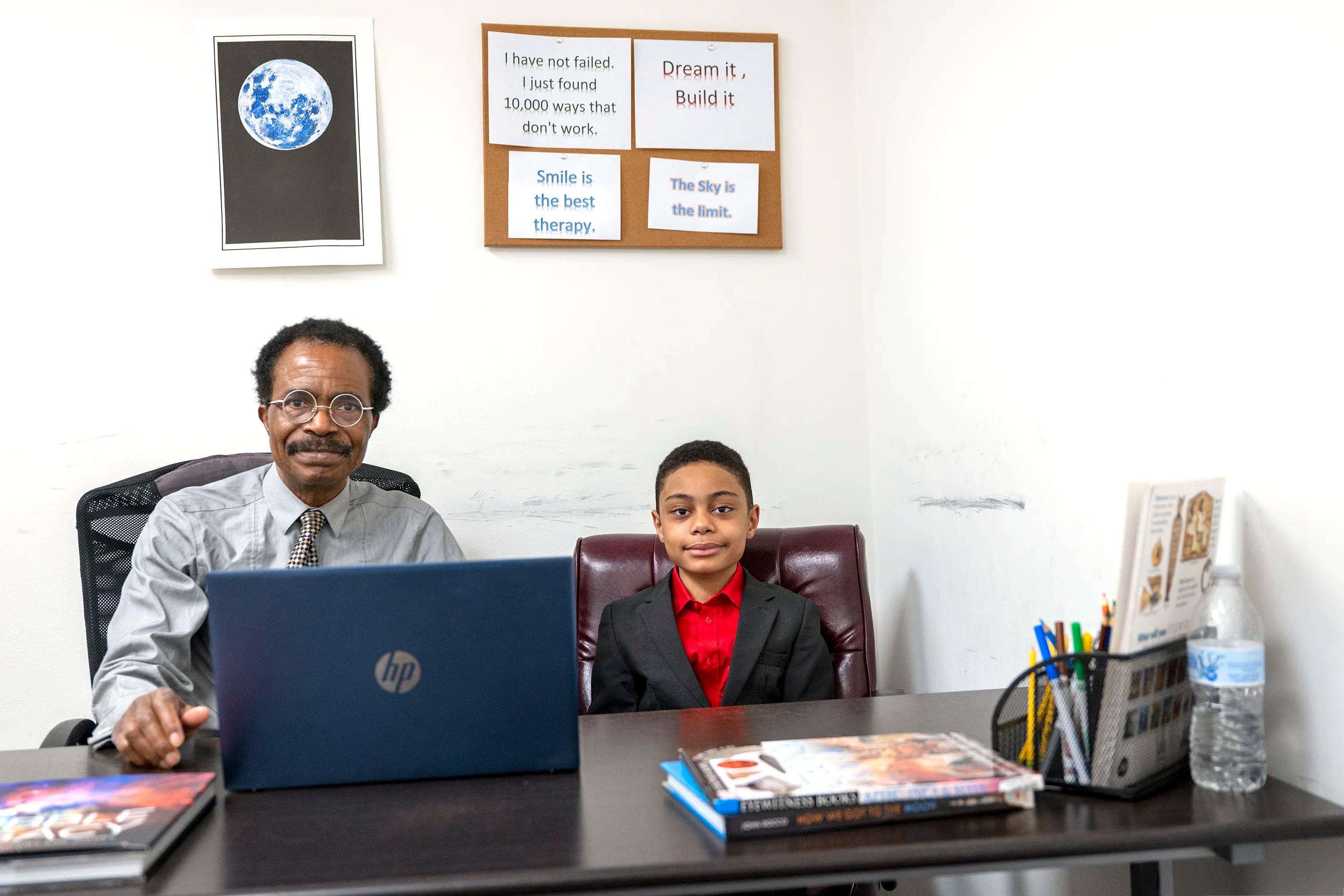 Henry Balogun poses with his 9-year-old wunderkind son David, at his office Wednesday, Feb. 8, 2023. Balogun, who just graduated from high school, one of the youngest people ever to do so, is into black holes and space theory and is contemplating where he'll attend college.