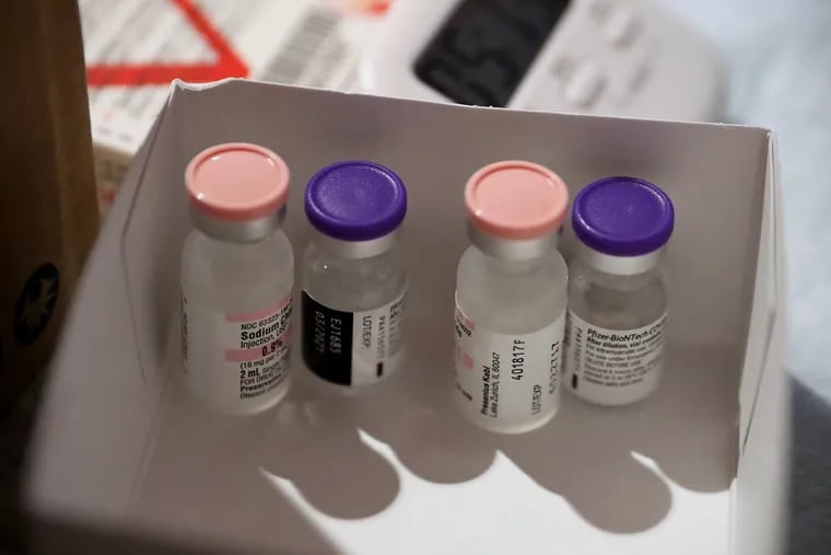 Vials of the Pfizer-BioNTech COVID-19 vaccine and saline solution sit out at room temperature before the vaccine can be reconstituted and administered at Temple University Hospital in North Philadelphia on Wednesday, Dec. 16, 2020.