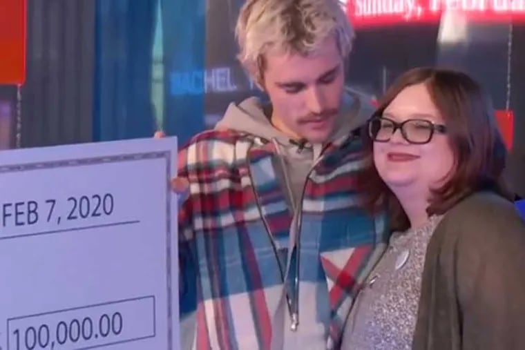 Justin Bieber presents Stockton University student Julie Coker with a $100,000 check.