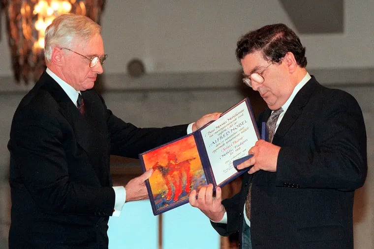 This Dec. 10, 1998 photo shows John Hume, right, looking at the Nobel Peace Prize diploma that he received from Francis Sejersted, left, chairman of the Norwegian Nobel Peace Prize Committee during the award ceremony in Oslo Town Hall.